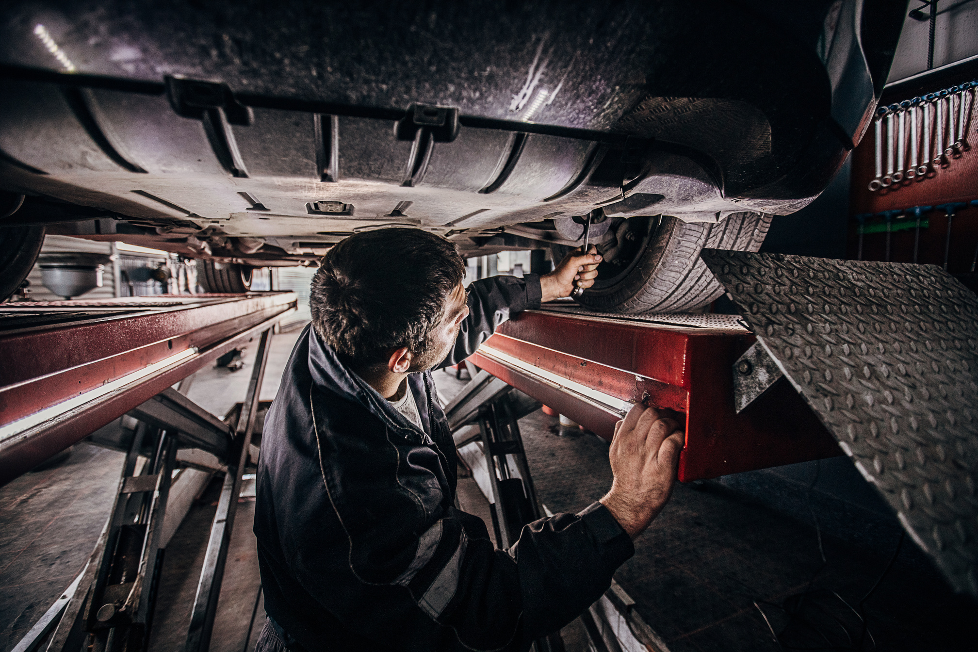 Car mechanic working beneath the car in workshop